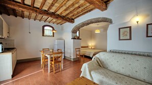 A cozy room with a wooden ceiling, a dining table with chairs, a bed, and a sofa.