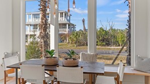 A dining area with a wooden table, white wicker chairs, and two woven planters. - Luxury Retreat w/Games, Patio, BBQ, Close to Beach (Palm Coast)