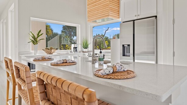 A modern kitchen with a large island, white cabinetry, and a view of the outdoors. - Luxury Retreat w/Games, Patio, BBQ, Close to Beach (Palm Coast)
