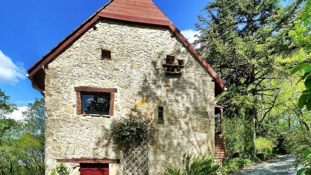 Un edificio de piedra con techo rojo, una ventana pequeña y una puerta roja.