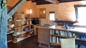 Una cocina rústica con estantes de madera, una estufa a gas y una estantería llena de libros.