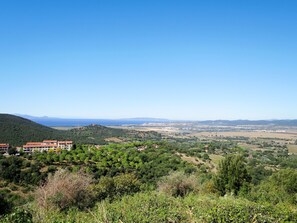 A view of a coastal town with buildings, green hills, and a clear blue sky. - Aba Village by Interhome (Scarlino)