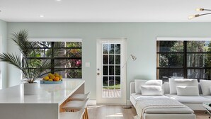 A modern kitchen with a white countertop, bar stools, and a potted plant. - Tranquil Oasis: Newly Renovated Villa, Heated Pool, Private Garden Retreat (Fort Lauderdale)