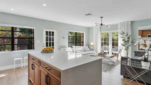 A modern kitchen with a large island, wooden cabinets, and a view of greenery outside. - Tranquil Oasis: Newly Renovated Villa, Heated Pool, Private Garden Retreat (Fort Lauderdale)