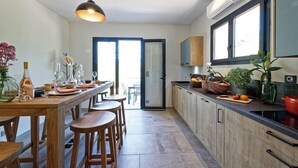 Una cocina moderna con una mesa de comedor de madera, taburetes y una lámpara colgante.