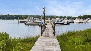 Une jetée en bois mène à une marina où plusieurs bateaux sont amarrés.