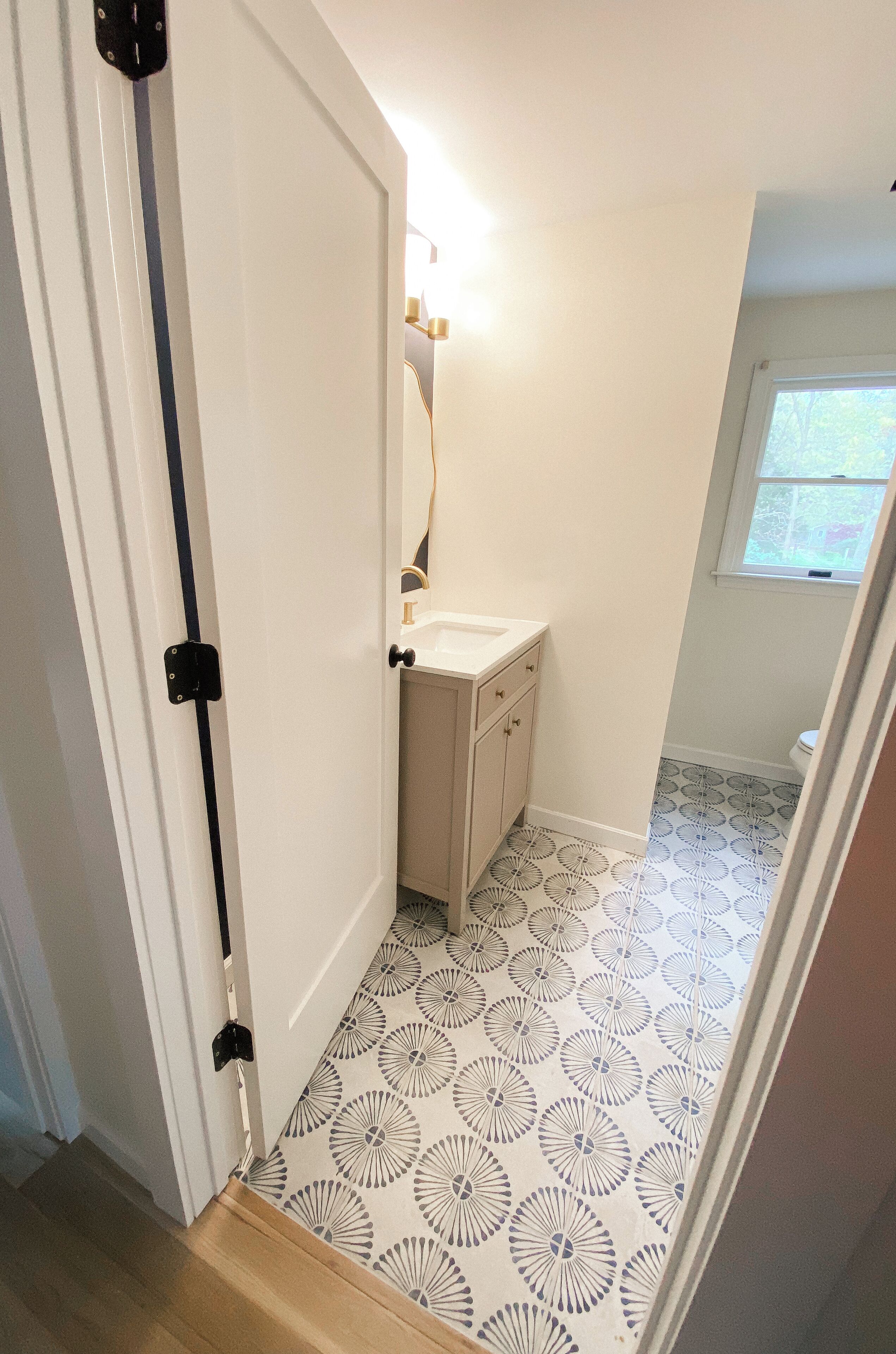 A bathroom with a patterned floor, a sink, and a window.