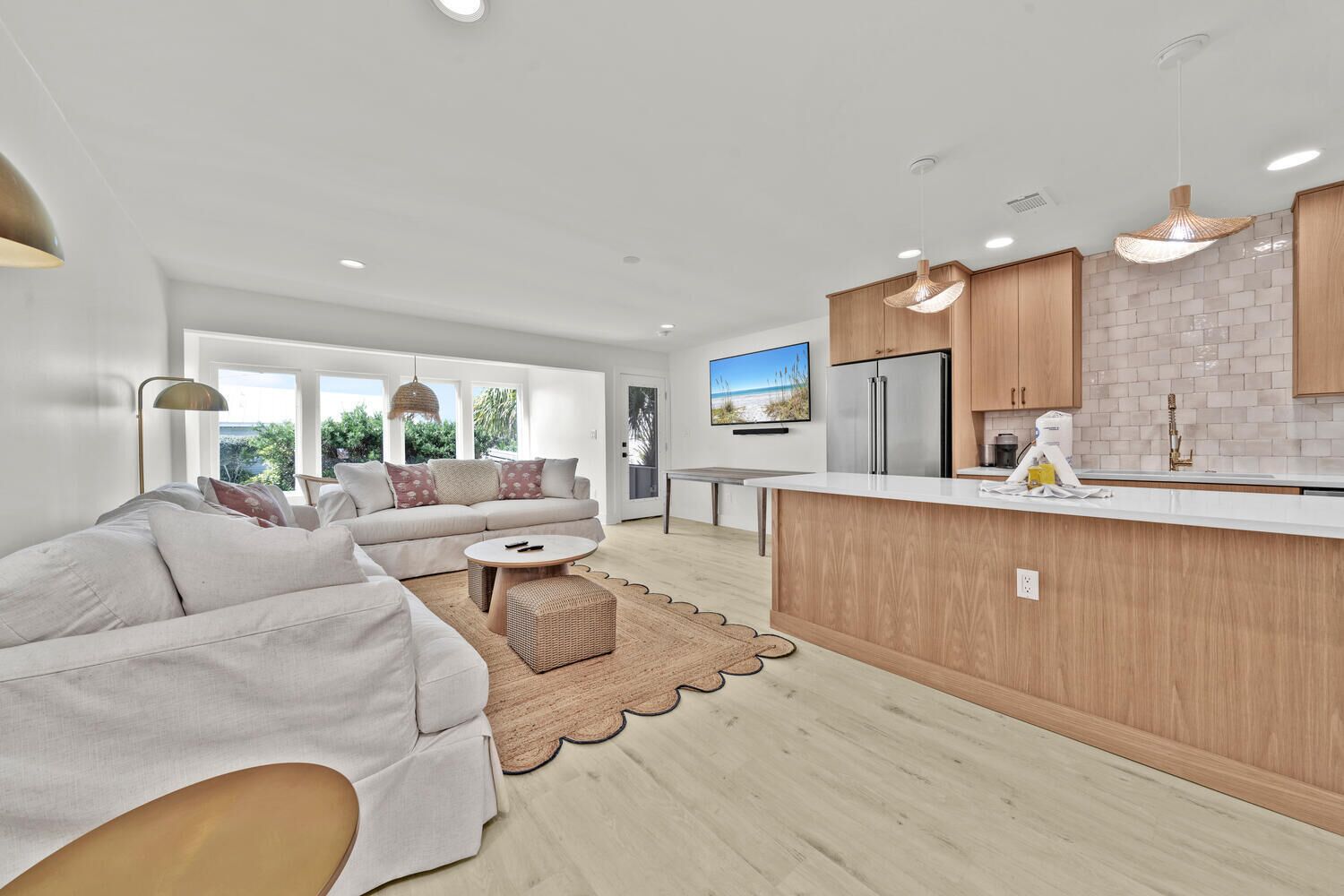 Een moderne keuken met een centraal eiland, houten kastjes en een groot raam met uitzicht op groen.