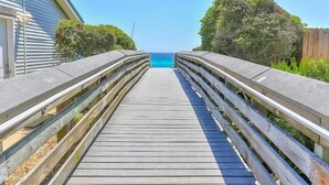 Una passerella in legno conduce a una spiaggia con vista libera sull'oceano.