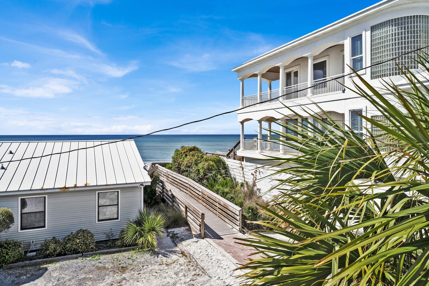 A coastal property with a wooden deck leading to a balcony overlooking the sea.