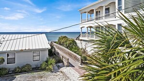 Un immobile costiero con un ponte di legno che conduce a un balcone con vista sul mare.