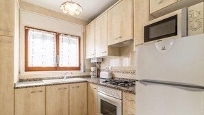 Eine Küche mit Holzausstattung, einem Spülbecken, einem Herd, einer Mikrowelle und einem Kühlschrank.