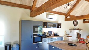 Een moderne keuken met ingebouwde apparatuur, een houten plafond en een klok aan de muur.