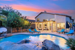 A house with a swimming pool, outdoor seating, and a covered patio area.