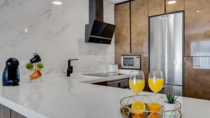 Une cuisine moderne dotée d’un plan de travail en marbre, d’appareils électroménagers en acier inoxydable et d’un four encastré.