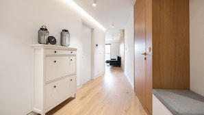 Ein Flur mit Holzboden, weißen Schränken und einer Bank.
