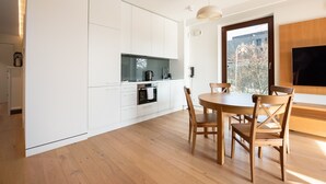 Eine moderne Küche mit weißen Schränken, einem eingebauten Ofen und einem Essbereich mit Holztischen und -stühlen.