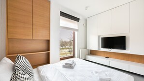 Ein modernes Hotelzimmer mit einem großen Bett, einem flachbildfernseher an der Wand und einem Fenster mit Blick ins Freie.