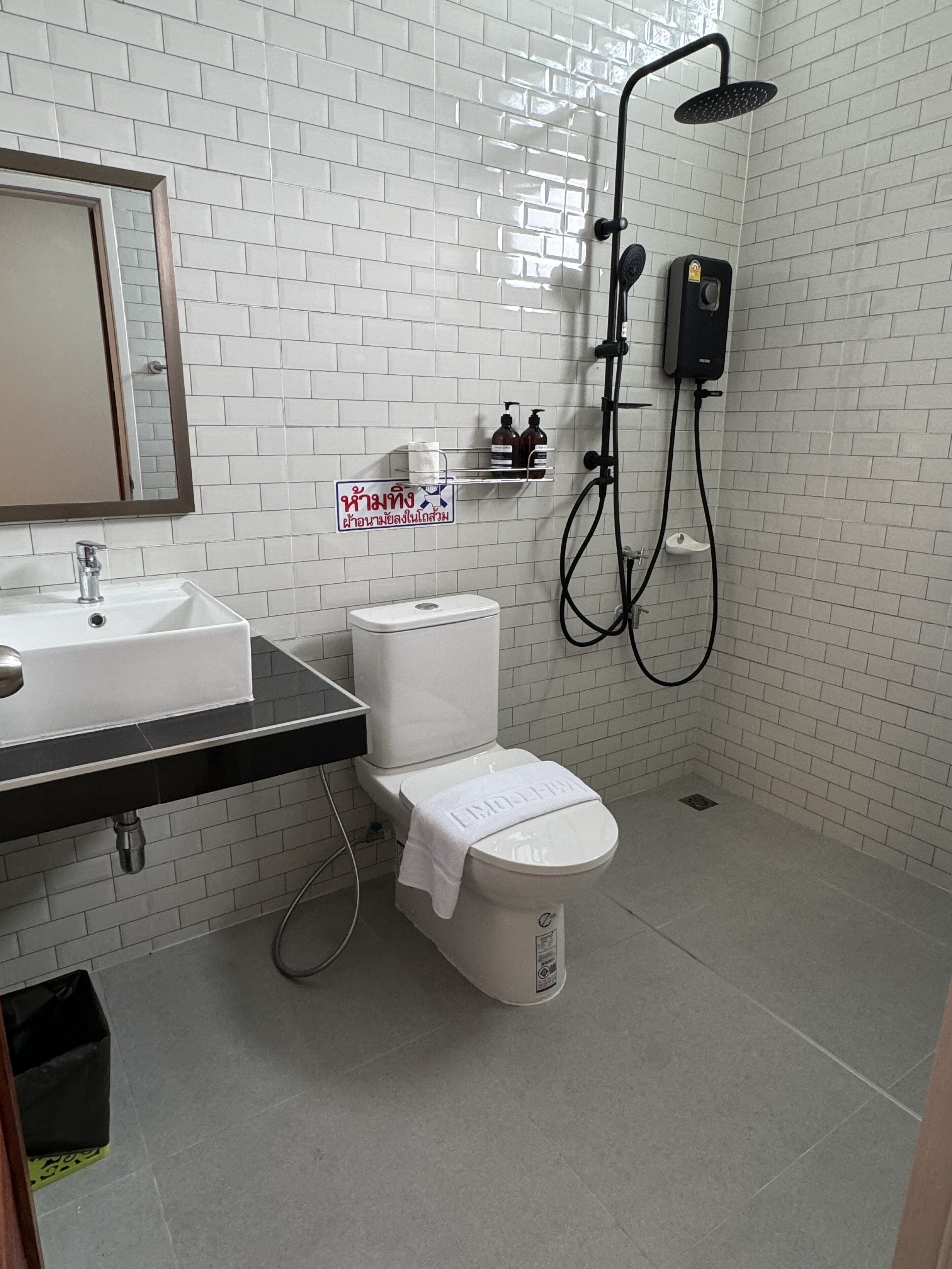 Une salle de bain avec des toilettes blanches, un lavabo et une douche.