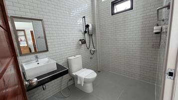 A modern bathroom with white brick walls, a large mirror, a sink, toilet, and a shower.