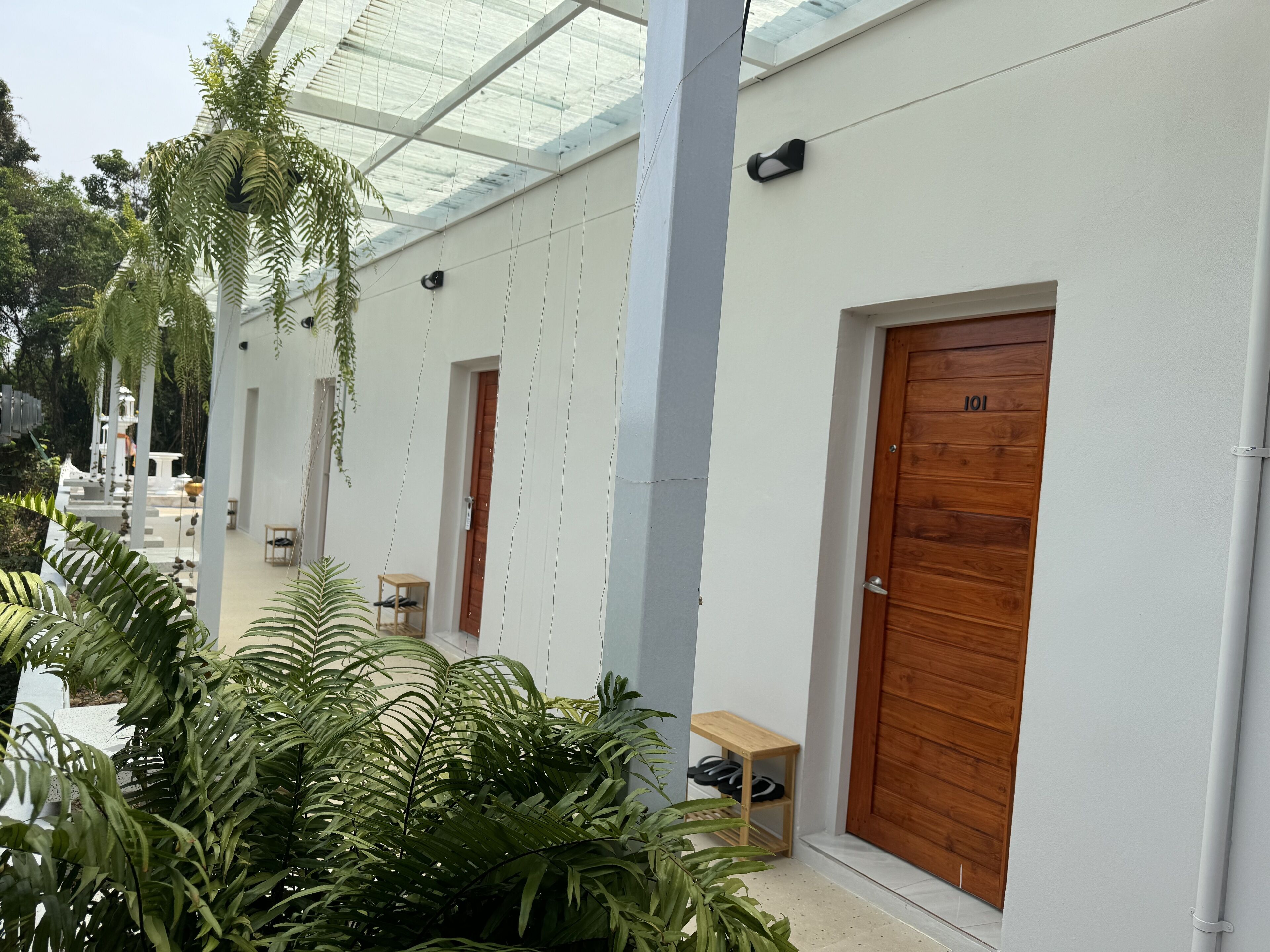 A modern building with white walls, wooden doors, and a glass ceiling.