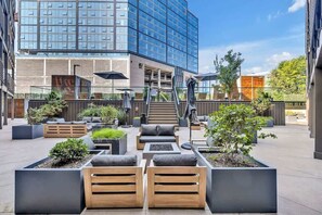 A modern outdoor seating area with planters, wooden benches, and umbrellas.