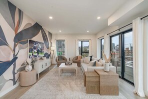 A modern living room with a sofa, armchairs, a coffee table, a cabinet, and a large abstract painting on the wall. - Hyve -Tropical Peach -Walk to Broadway - Pool&Gym! (Nashville)