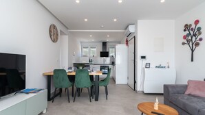 A modern living room with a grey sofa, a wooden coffee table, and a dining area with green chairs and a white table. - Apartment M&M 1 by Interhome (Kaštela)