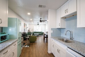 A kitchen with white cabinets, a teal refrigerator, and a sink with a blue tiled backsplash. - Biltmore Bungalows Triplex w/Heated Pool, Carports, 9 Smart TVs, W/D, Fast WiFi (Phoenix)