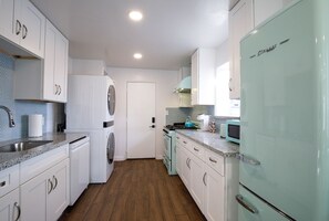 A kitchen with white cabinets, a turquoise refrigerator, and a wooden floor. - Biltmore Bungalows Triplex w/Heated Pool, Carports, 9 Smart TVs, W/D, Fast WiFi (Phoenix)