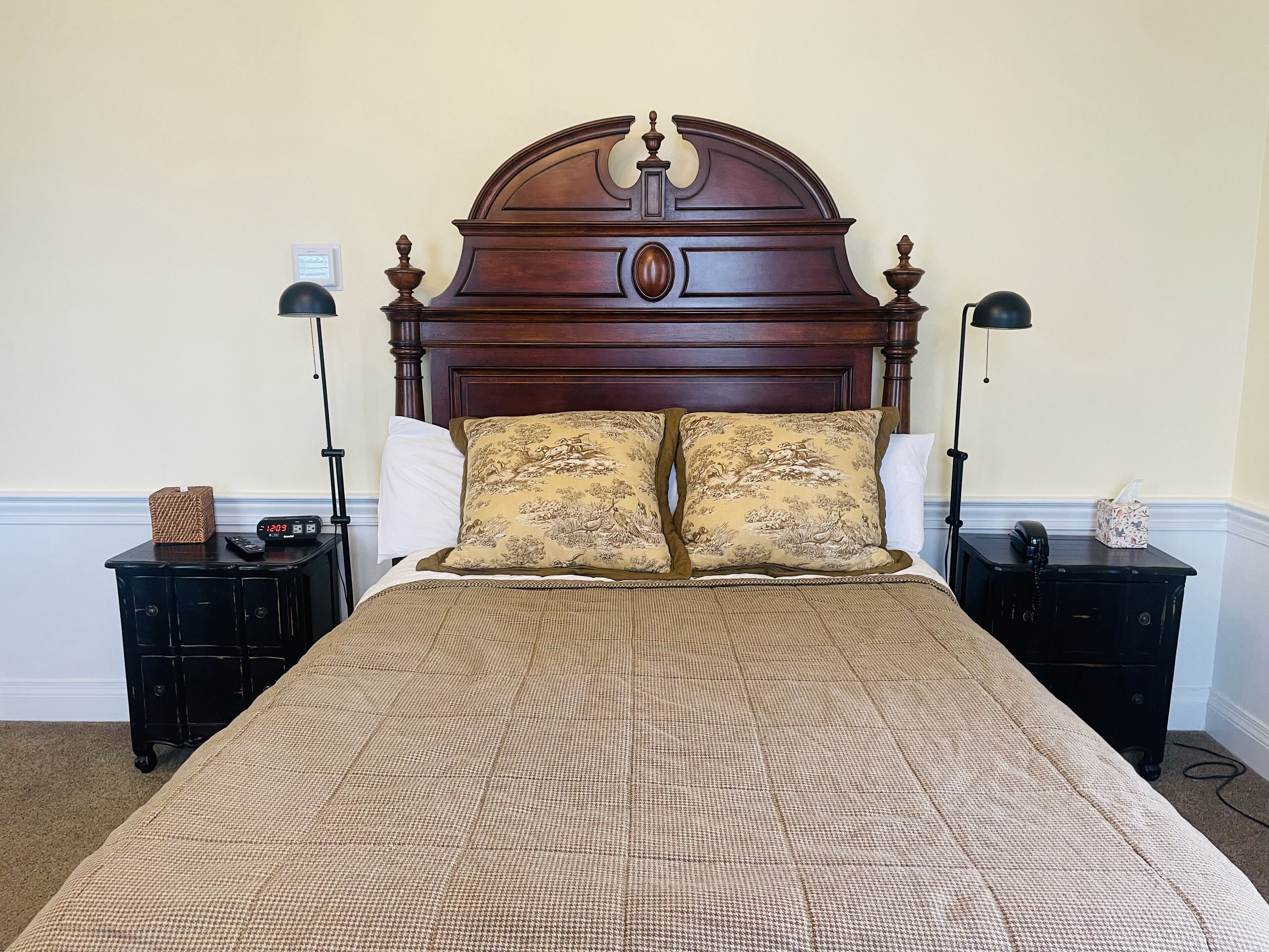 A bed with a wooden headboard, two bedside tables, and lamps.