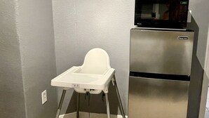 A kitchen with a white high chair, a stainless steel refrigerator, and a microwave on top. - XL Sacramento Studio Midtown Downtown NEWLY Renovated - Work Play Stay (Sacramento)