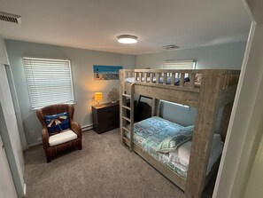 Ein Schlafzimmer mit Etagenbetten, einem Sessel, einem Nachttisch und einem Wandbild.