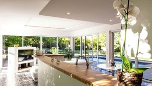 Una cocina moderna con una isla grande, horno empotrado y vistas a una piscina.