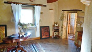 A room with a large window, a wooden table, a rug, and a stone wall. - Maison De Charme Dans Le (Brech)