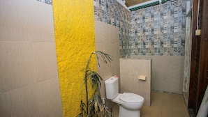 Un baño pequeño con inodoro, pared amarilla y azulejos estampados.