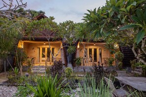 A two-story wooden house with a stone pathway leading to the entrance. - Desa Sweet Cottages (Ceningan Island)