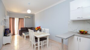 A modern living room with a sofa, dining table, and kitchen area.
