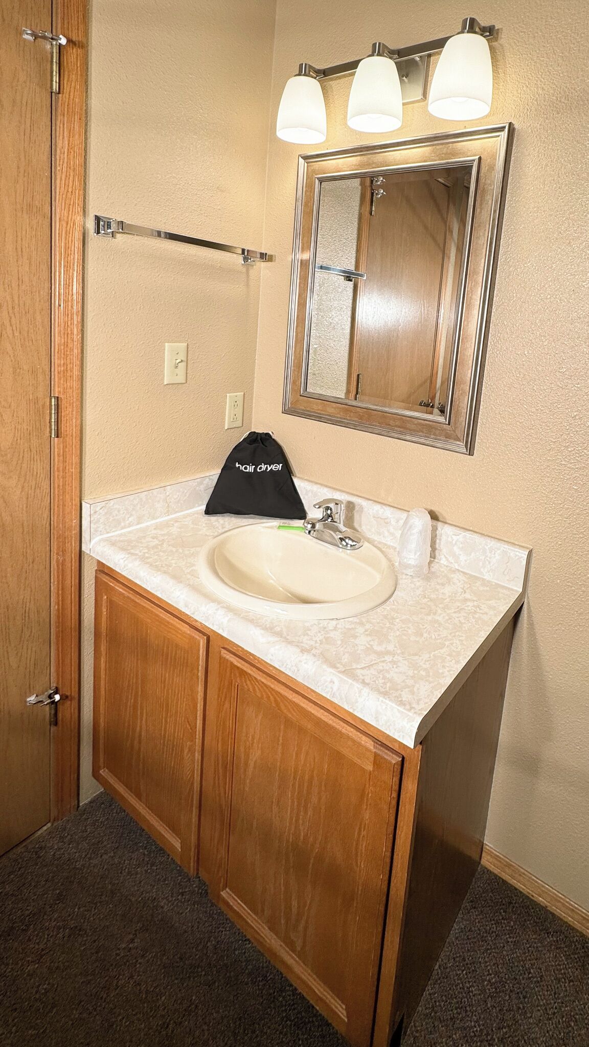 A bathroom with a wooden vanity, a sink, a mirror, and a towel rack.