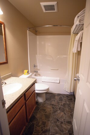 A bathroom with a shower, toilet, and sink.