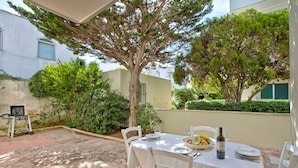 An outdoor dining area with a table set for two, surrounded by greenery and a tree. - Residence Thalassa with Shared Pool, 100m to the Beach, Melendugno, Italy (Melendugno)