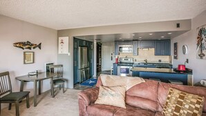A living room with a brown sofa, a coffee table, and a dining area with chairs and a table. - Gearhart House G638 (Gearhart)