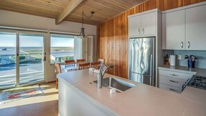 Cozinha moderna com uma ilha grande, eletrodomésticos de aço inoxidável e vista para o exterior.