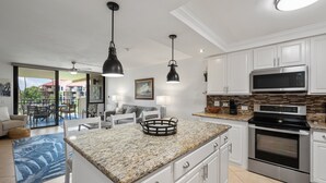 A modern kitchen with white cabinets, a built-in microwave, and an oven. - Remodeled Condo Across Beach w Pool AC - Kamaole Sands 7307 (Kihei)