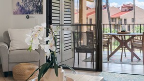 A living room with a sofa, a coffee table, and a potted orchid. - Remodeled Condo Across Beach w Pool AC - Kamaole Sands 7307 (Kihei)