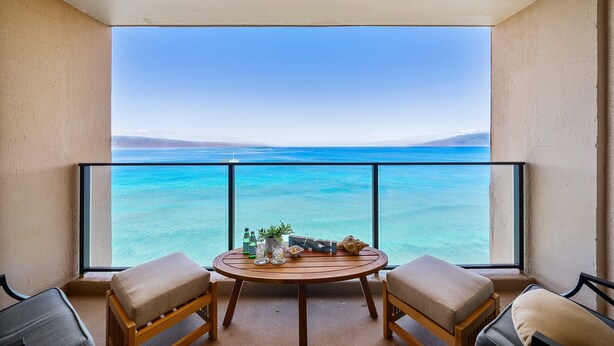 Un balcon avec une table, deux chaises et une vue sur l’océan.