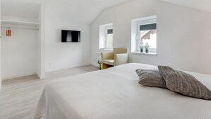 Une chambre à coucher avec un lit, une télévision, une chaise et une fenêtre.