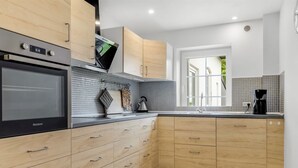 Une cuisine moderne avec des meubles en bois, un four noir et un pare-feu en carreaux.