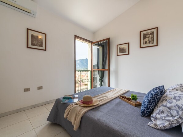 Un dormitorio con cama, ventana con vistas y cuadros en la pared.