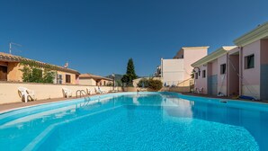 Una piscina con acqua cristallina e cielo sereno, circondata da edifici con balconi.